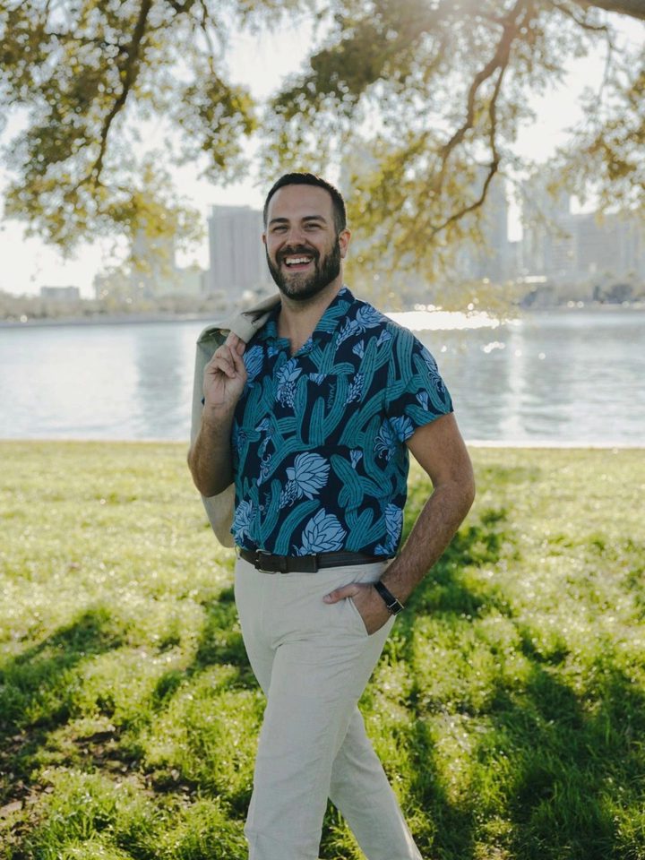 Anthony Dominic, Realtor®, standing on the waterfront with the downtown St. Petersburg skyline behind him